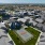 Aerial view of a modern residential community featuring single-story homes, a large central green space, and scenic desert surroundings under a bright sky