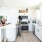 Bright modern kitchen with white cabinets, stainless steel appliances, and a group of residents enjoying a conversation at the kitchen island
