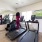 Modern fitness center with a woman using a treadmill, large wall-mounted TV, mirrored walls, and various exercise equipment