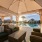 Outdoor lounge area with woven chairs, a cushioned sofa, and a round coffee table, overlooking a pool with modern townhomes in the background