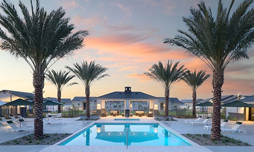 resort style pool with seating palm trees and a building behind it